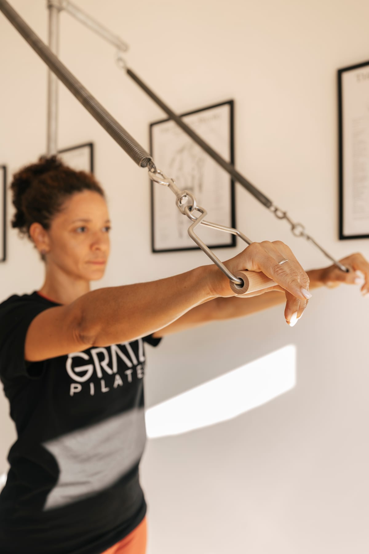 Chris Pinheiro trabajando con el brazo extendido en un aparato clásico de Pilates con muelles, en el estudio Essentia