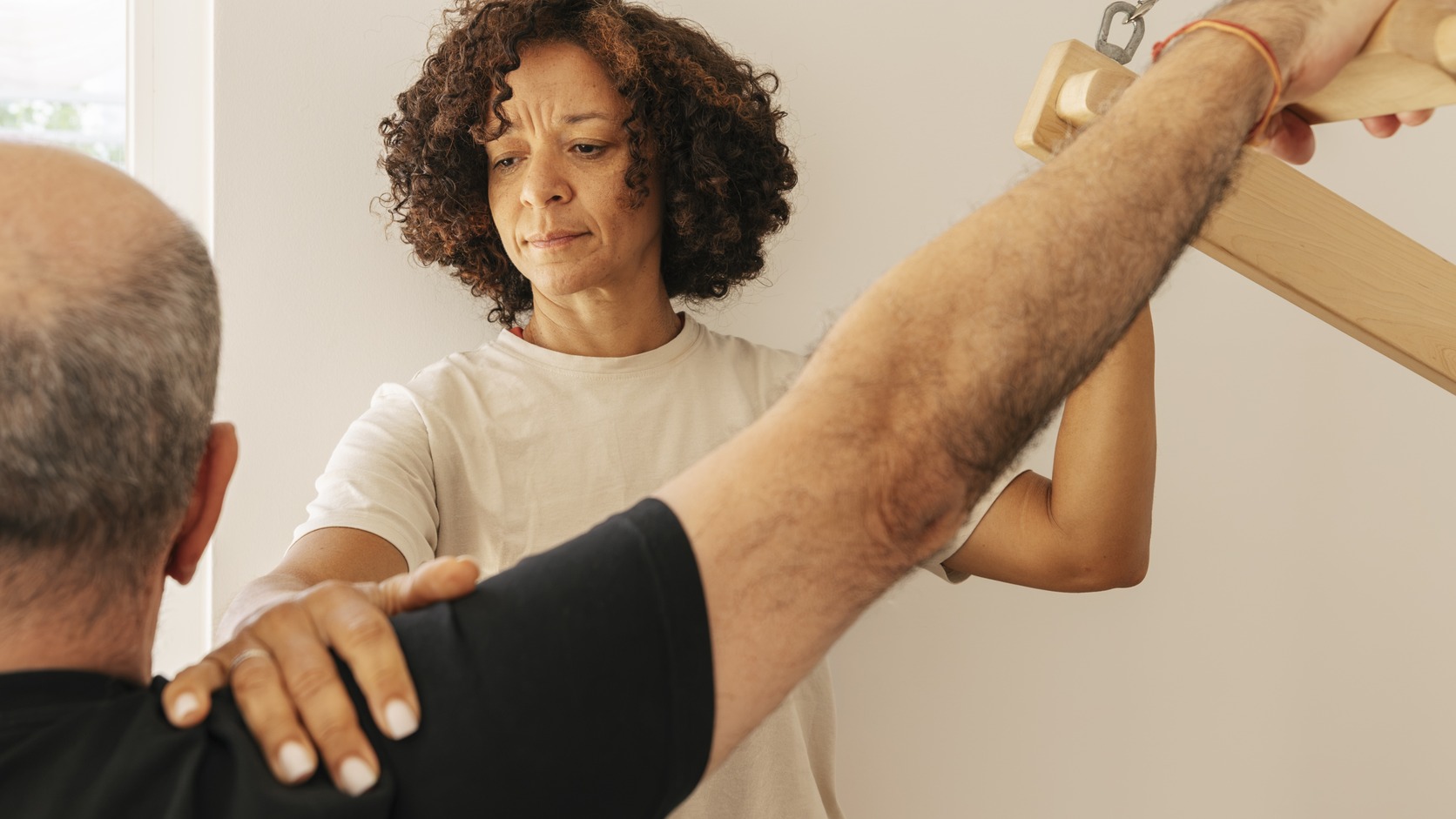 Instructora de Pilates guiando y corrigiendo la postura de un alumno durante un ejercicio con aparato